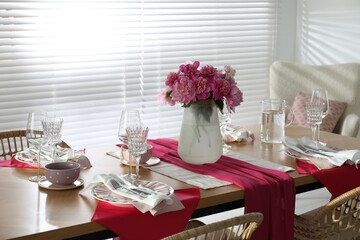 Pink peonies on table with beautiful setting in dining room
