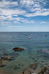 Boats anchored near a rocky cove in Calella de Palafrugell, a fishing village on the Costa Brava in Catalonia, Spain. Vertical photography.

