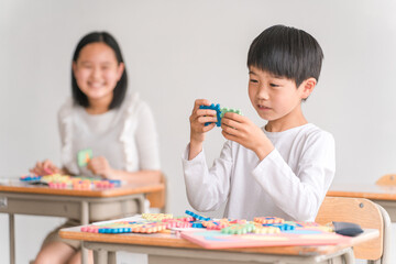 学校の教室でアルファベットのおもちゃを使って英語を勉強する小学生の男の子（低学年）
