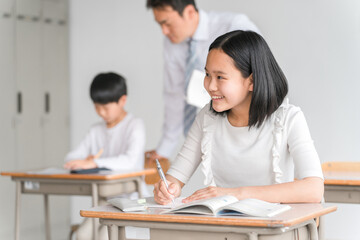 学校の教室で楽しく勉強する笑顔の高学年の小学生の男女（塾・夏期講習）と男性教師
