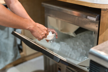 製氷機の氷をグラスに入れるスタッフ・従業員の男性の手元

