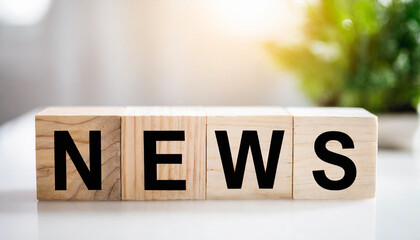 Wooden blocks spell "NEWS" on a white table, with a blurred newsroom background, symbolizing communication, media, and information dissemination