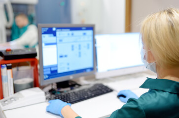 Female radiologist is going to take X ray of patient in X-ray room of modern clinic. Close up photo of doctor hand presses button for execute of medical examination