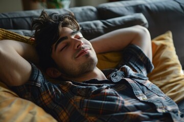 Obraz premium Man Relaxing on Couch at Home. Young Man Resting and Practicing Mindfulness on Sofa