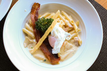 Penne carbonara creamy with bacon and fresh egg in white plate, Italian food. Delicious Italian pasta. 