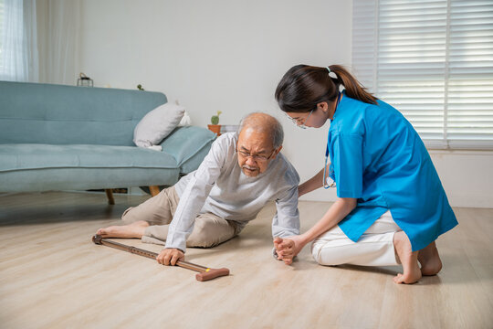Disabled elderly man patient with walking stick fall on ground and caring assistant at nursing house, Asian senior old man falling down on lying floor and woman nurse helping support in living room