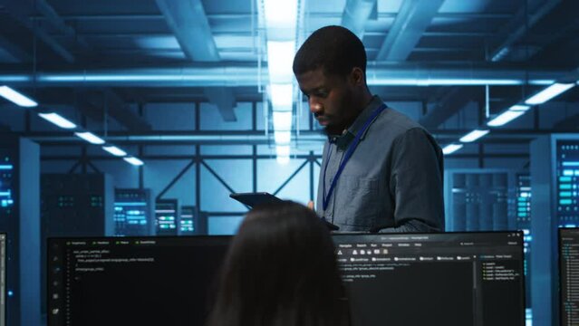 Manager uses tablet, supervising team programming servers providing computing resources for different workloads. Inspector using device to oversee engineers in data center mending supercomputers