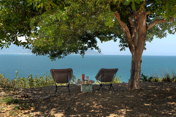 Nha Trang City, Vietnam - March 30, 2024: Woman resting under the shade of a tree looking out to sea. Relaxation concept