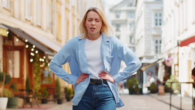 Caucasian young woman traveler feeling sudden strong abdominal stomach ache gastritis problem. Upset tourist lady having symptom poisoning diarrhea indigestion peptic ulcer pancreatitis on city street
