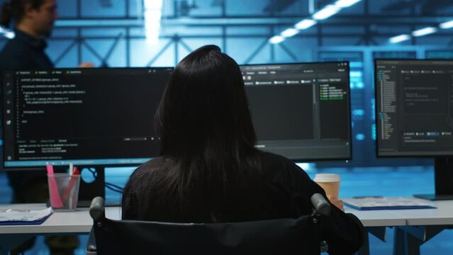 Person with paraplegia in server hub workplace doing inspection on electronics, reading files. Wheelchair user at work looking over paperwork, verifying infrastructure documents, doing audit