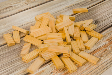 A pile of scattered wooden blocks on a light wooden tabletop background