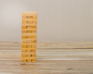 A tall, neatly stacked tower of wooden blocks on a wooden tabletop. Generic version of popular game.