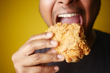 Man enjoying fried chicken, mouth open, savoring every bite with a big smile