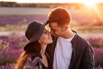 Close-up of a young man and woman in love in the field, watching the sunset.