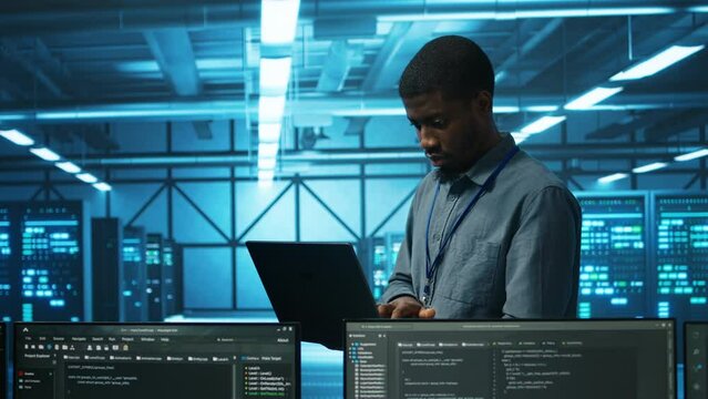 Manager in server hub using laptop to find firewall misconfigurations affecting rackmounts performance. Supervisor checking systems bottlenecks leading to sluggish data transfer rates