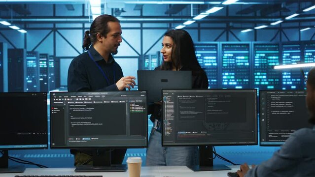 Programmer and supervisor in server room looking for equipment misconfigurations, doing brainstorming. Multiracial colleagues checking data center gear bottlenecks leading to glitches