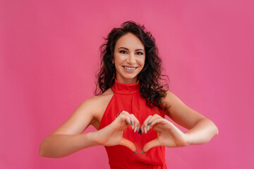 A woman in a red dress is smiling and holding her hands together to make a heart shape. Concept of...