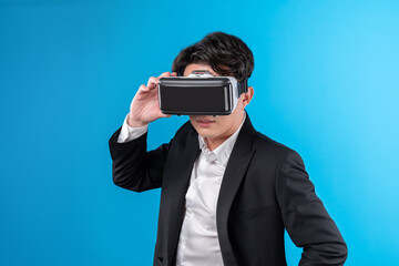Smiling Asian businessman looking thorough VR connecting to business world report in futuristic...