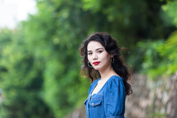 Fototapeta premium Outdoors a curly-haired Chinese beauty in a denim skirt