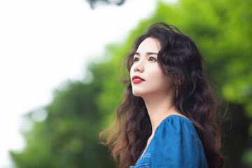Naklejka premium Outdoors a curly-haired Chinese beauty in a denim skirt