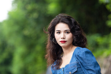 Naklejka premium Outdoors a curly-haired Chinese beauty in a denim skirt