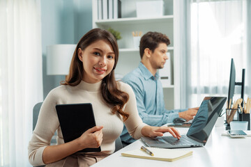 Smiling beautiful woman working on laptop aligning taking note to pose for looking at camera photo...