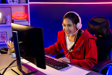 Host channel of smiling beautiful Asian girl streamer playing online game wearing headphone talking with viewers media online recording phone. Esport skilled team players in neon blue room. Stratagem.
