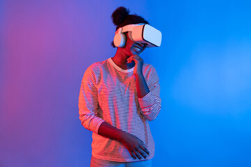 Young African woman with VR in presentation through metaverse study online neon studio lighting background in 3D technology innovation hologram technology application in user experience. Contrivance.