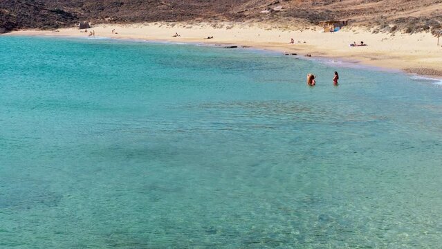 Paralia Agios Sostis wild and free beach in the north of Mykonos, Greece. Pristine bay with blue sea and crystal water, famous for naturism and Kiki's Tavern, peaceful and quiet. Gimbal cinematic