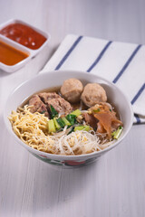Meatballs or Bakso, one of Indonesian specialties. Served with yellow noodles, vermicelli and vegetables in a white bowl