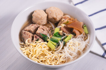 Meatballs or Bakso, one of Indonesian specialties. Served with yellow noodles, vermicelli and vegetables in a white bowl