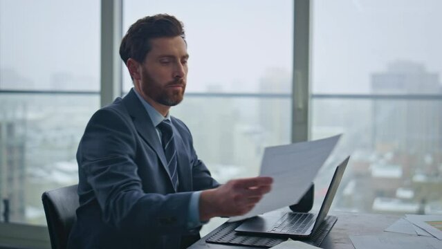 Busy accountant working laptop sitting office looking documents at desk closeup