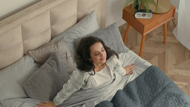 Top view brunette woman wake up checking time in smartphone mobile phone late rush for work university get out of bed quickly fast speedy oversleep home inside bedroom sleeping female lying lateness