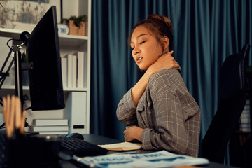 Businesswoman working on computer with stretching arm up and down manner with body health ache of...