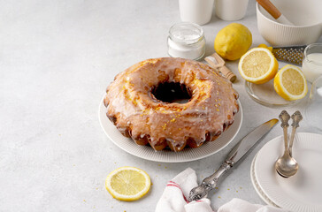 Lemon bundt cake drizzled with powdered sugar glaze on a light table with copy space for recipe