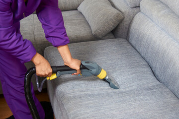 A person is cleaning a couch with a steam cleaner