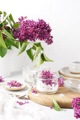 Preparation of syrup from the flowers of lilac in glass jar with sugar. White background. Selective focus. vertical copy space