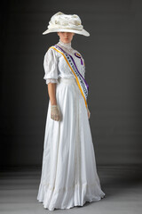 American Victorian or Edwardian Suffragette with historically accurate purple and gold sash and and rosette against a plain studio backdrop