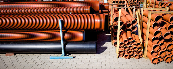 Warehouse of orange plastic sewer pipes.