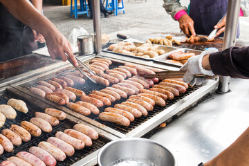 Close-up of the vendors grilling Taiwanese sausage and sticky rice (glutinous rice) sausage in the night market in Taiwan. This is one of the street snacks popular among tourists in Taiwan.