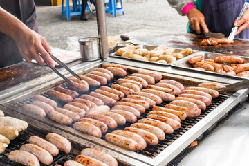 Close-up of the vendors grilling Taiwanese sausage and sticky rice (glutinous rice) sausage in the night market in Taiwan. This is one of the street snacks popular among tourists in Taiwan.