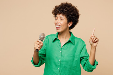Young singer fun woman of African American ethnicity wear green shirt casual clothes sing song in...
