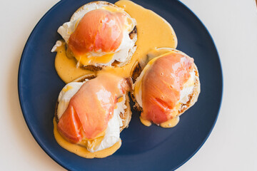 Toast with eggs Benedict and salmon with hollandaise sauce on a blue plate