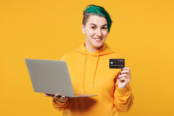 Young IT woman with dyed green hair wear hoody casual clothes using laptop pc computer hold credit...