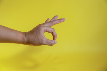 human hand gesturing approval expression doing okay symbol with fingers isolated on yellow...