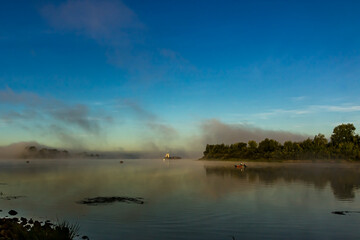 Fishermen on  boats early in the morning at dawn in the fog at golden hour catch fish on the Oka...