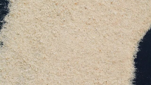 Closeup of sand transition blowing over black abstract background in slow motion