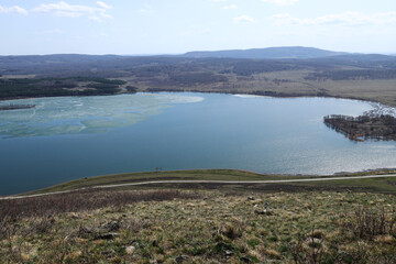 spring melting ice on a lake, a road along a pond and an island covered in forest