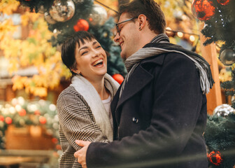 laughing couple falling in love hugging in Christmas market lifestyle photo	