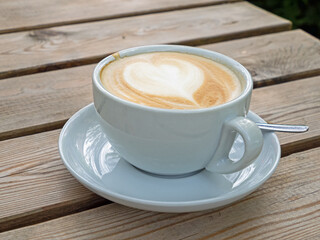Nahaufnahme einer Tasse mit Milchkaffee auf einem hölzernen Tisch
